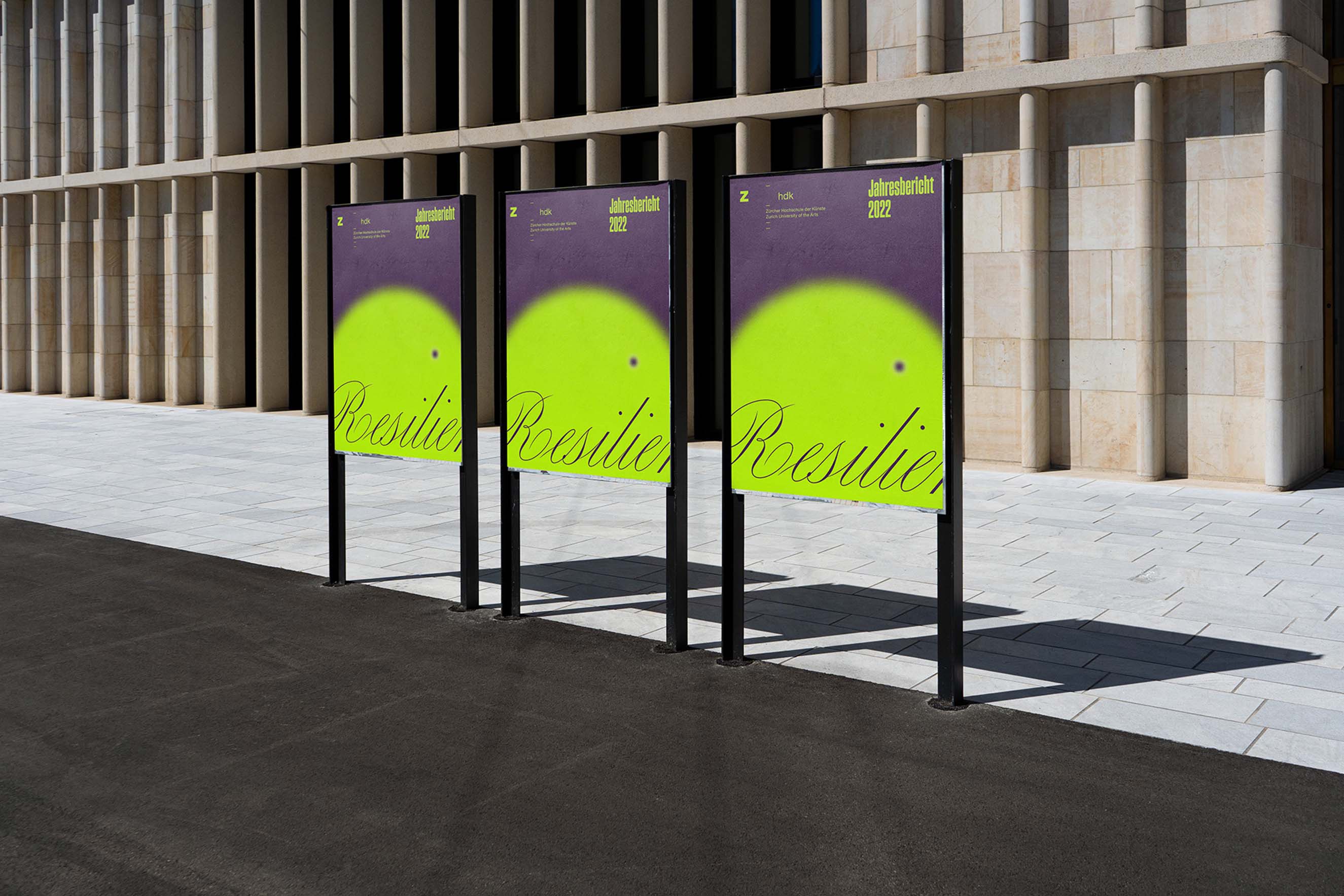 Large-scale outdoor posters for the ZHdK 2022 Annual Report mounted on a modern building in Zurich. The design features a grainy, lime-green sphere on a deep purple background with the word "Resilienz" in elegant, overlapping script, showcasing the studio's creative direction and environmental branding capabilities.