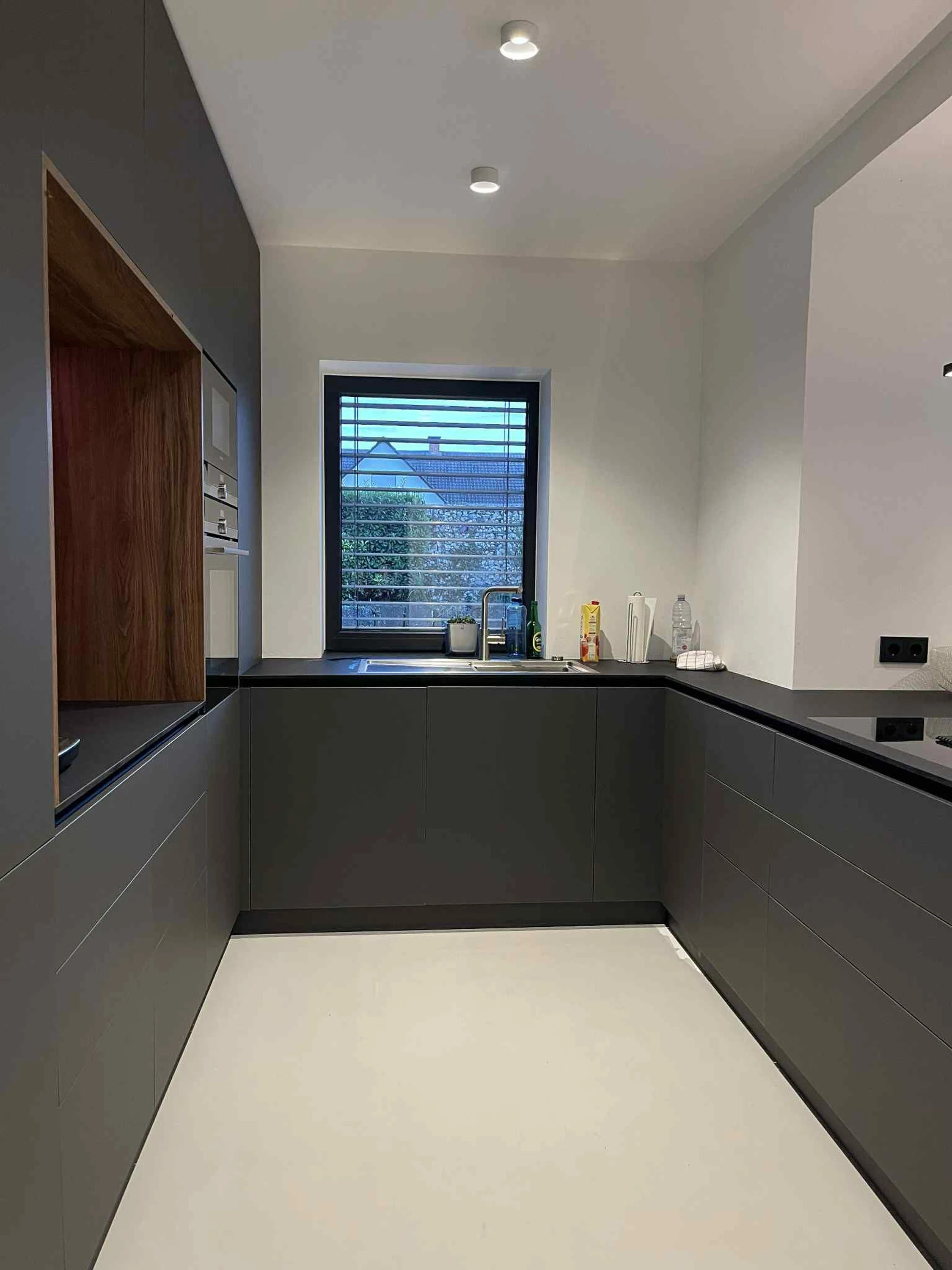 Cuisine noire et grise de nuit : îlot avec plaque à induction, fours encastrés, éclairage LED périphérique — réalisation sur mesure.