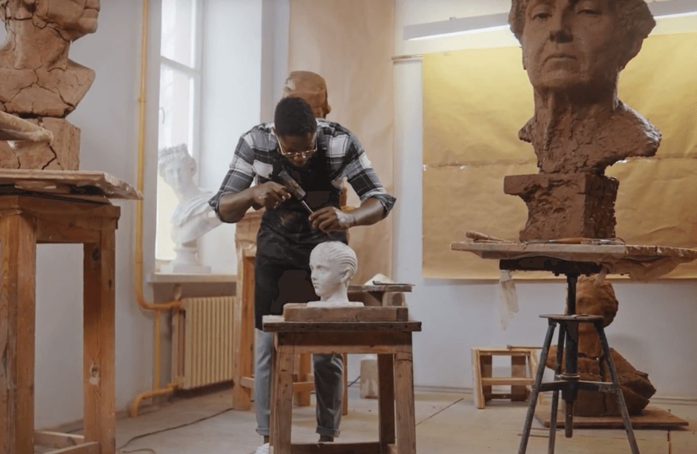 Video still of a museum conservator doing on reparation work on a marble bust