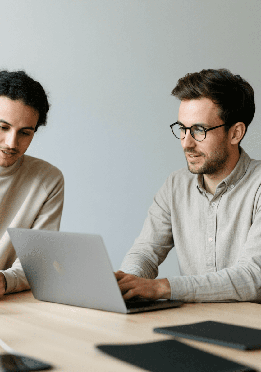 Two people, one with glasses, looking at a laptop together.