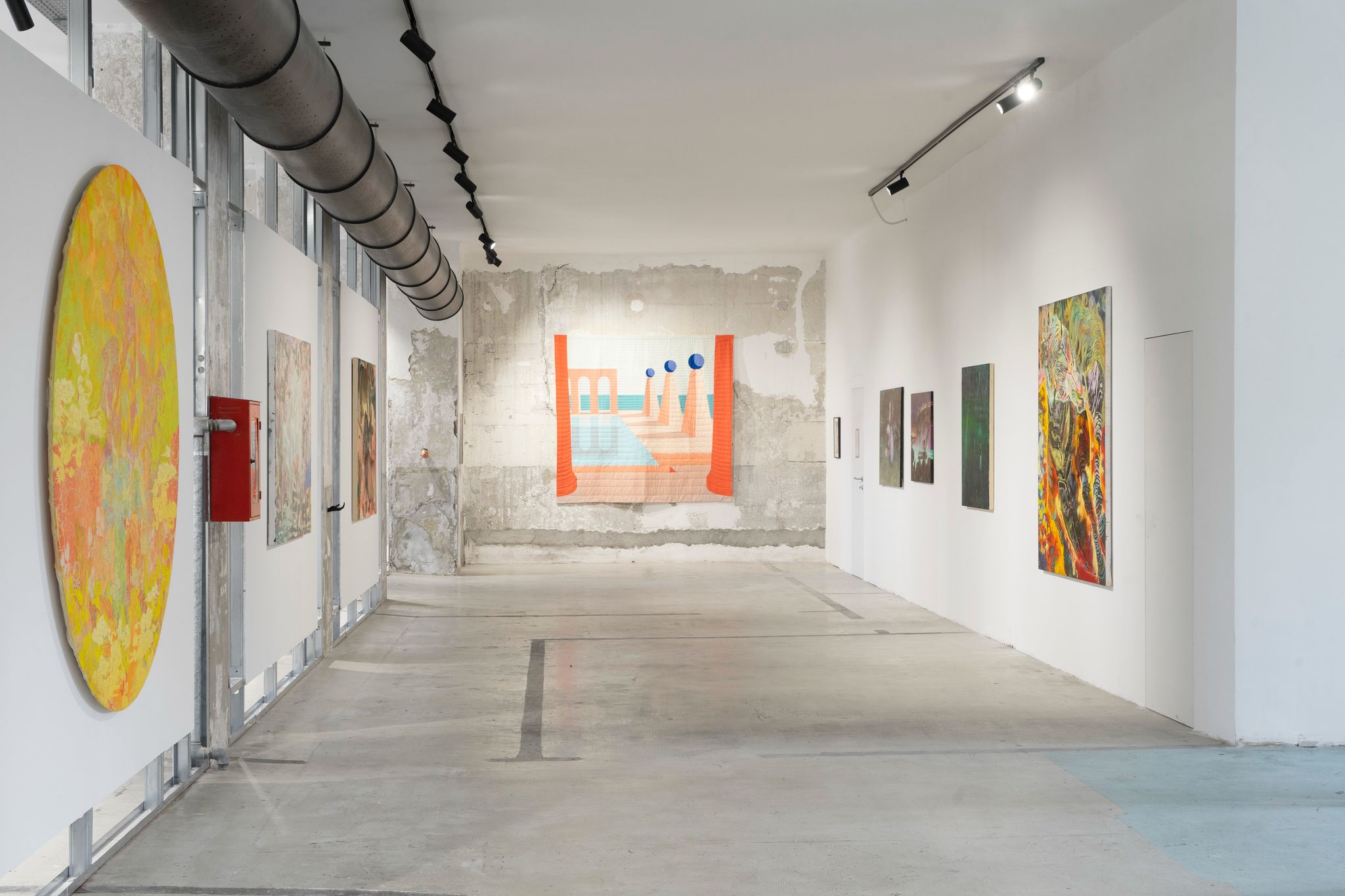 Smiling man working on a laptop at a desk, seated in front of a colorful abstract painting