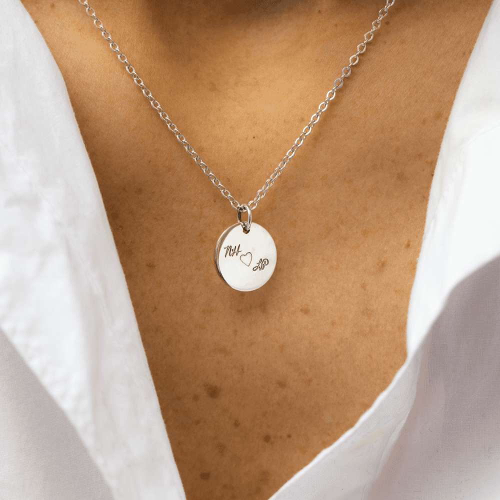 A woman wearing a silver Night Sky Love Note pendant with the letters "NH" and "LP" with a heart in between. 