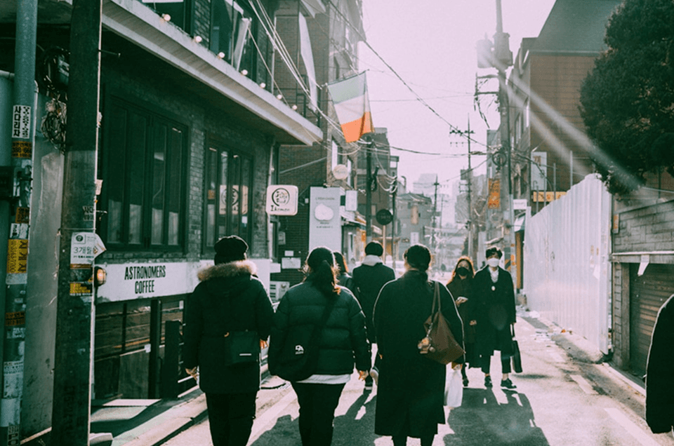 A green-tinted city street with people walking in the foreground, symbolizing the best Influ2 alternatives for person-based advertising in 2026.