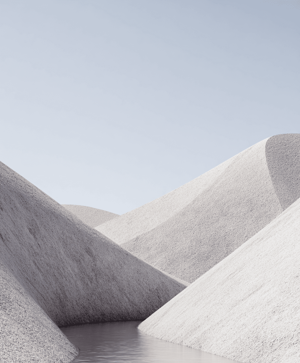 Soft white dunes slope into a narrow, glass-calm channel of water under a pale blue sky, creating a peaceful, minimalist desert scene.
