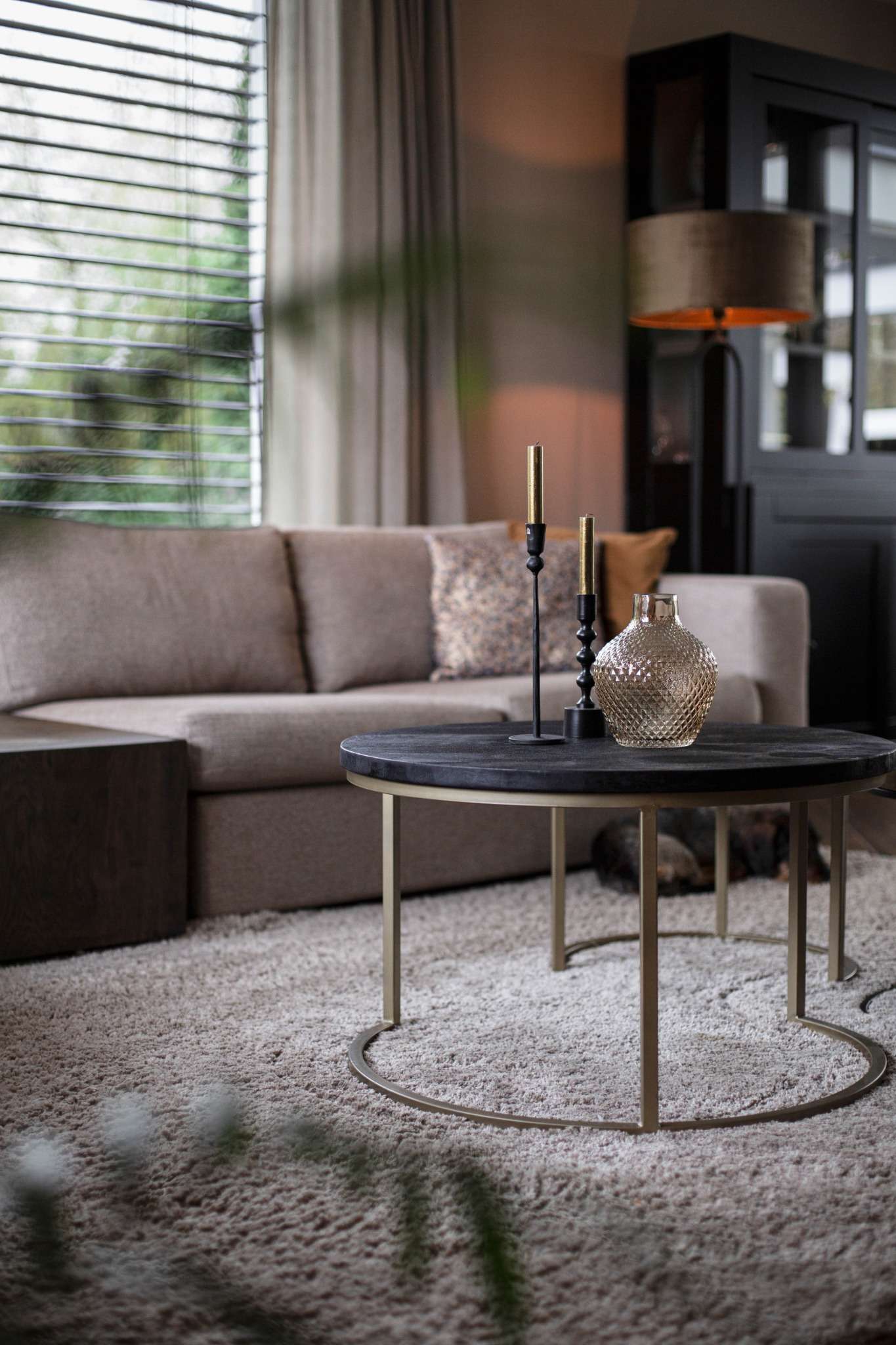 Woonkamer met grote hoekbank, warme tinten, houten vloer en rustige styling in een rietgedekte villa.