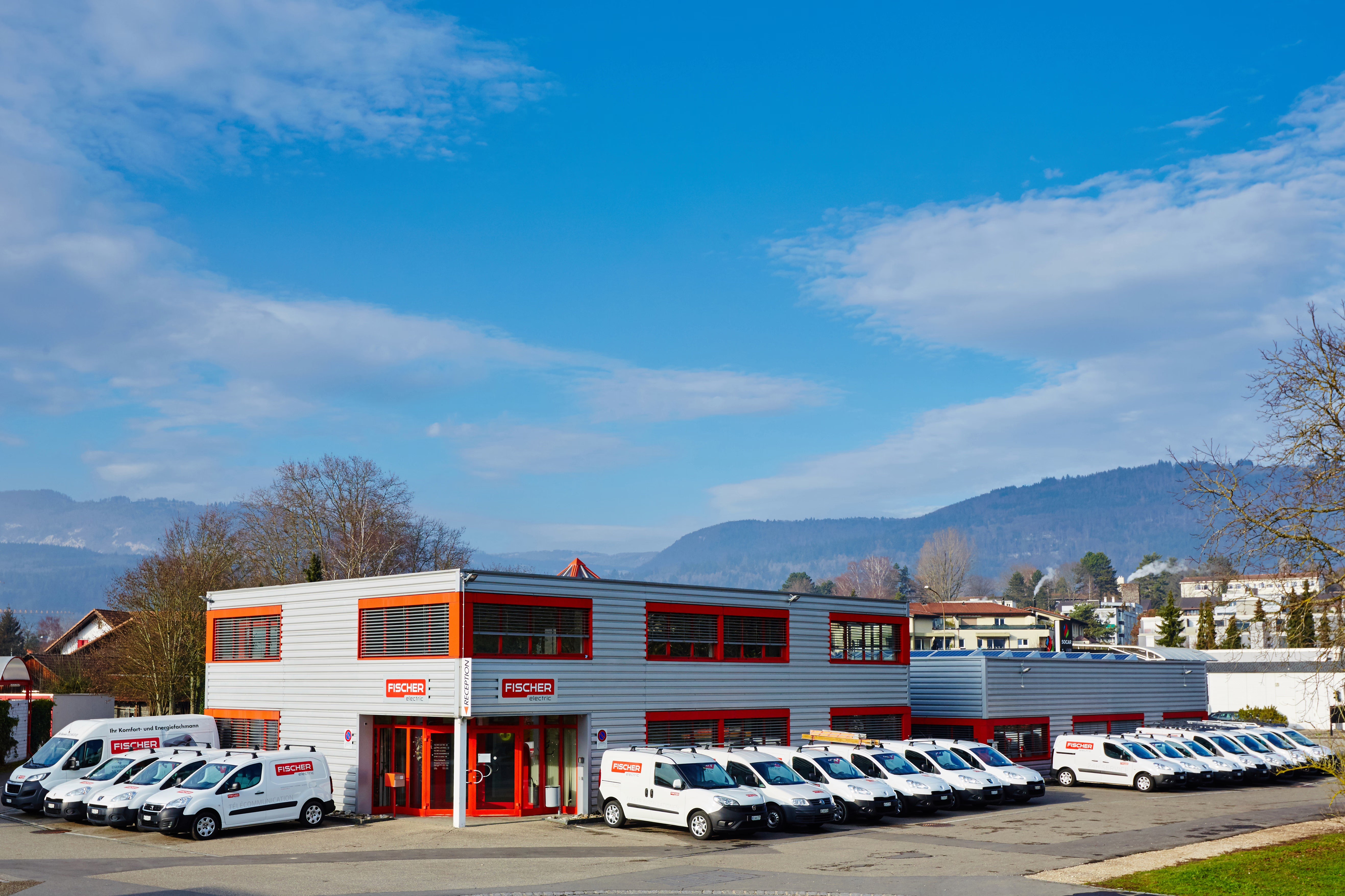 Bâtiment de Fischer Electric avec des véhicules de service devant
