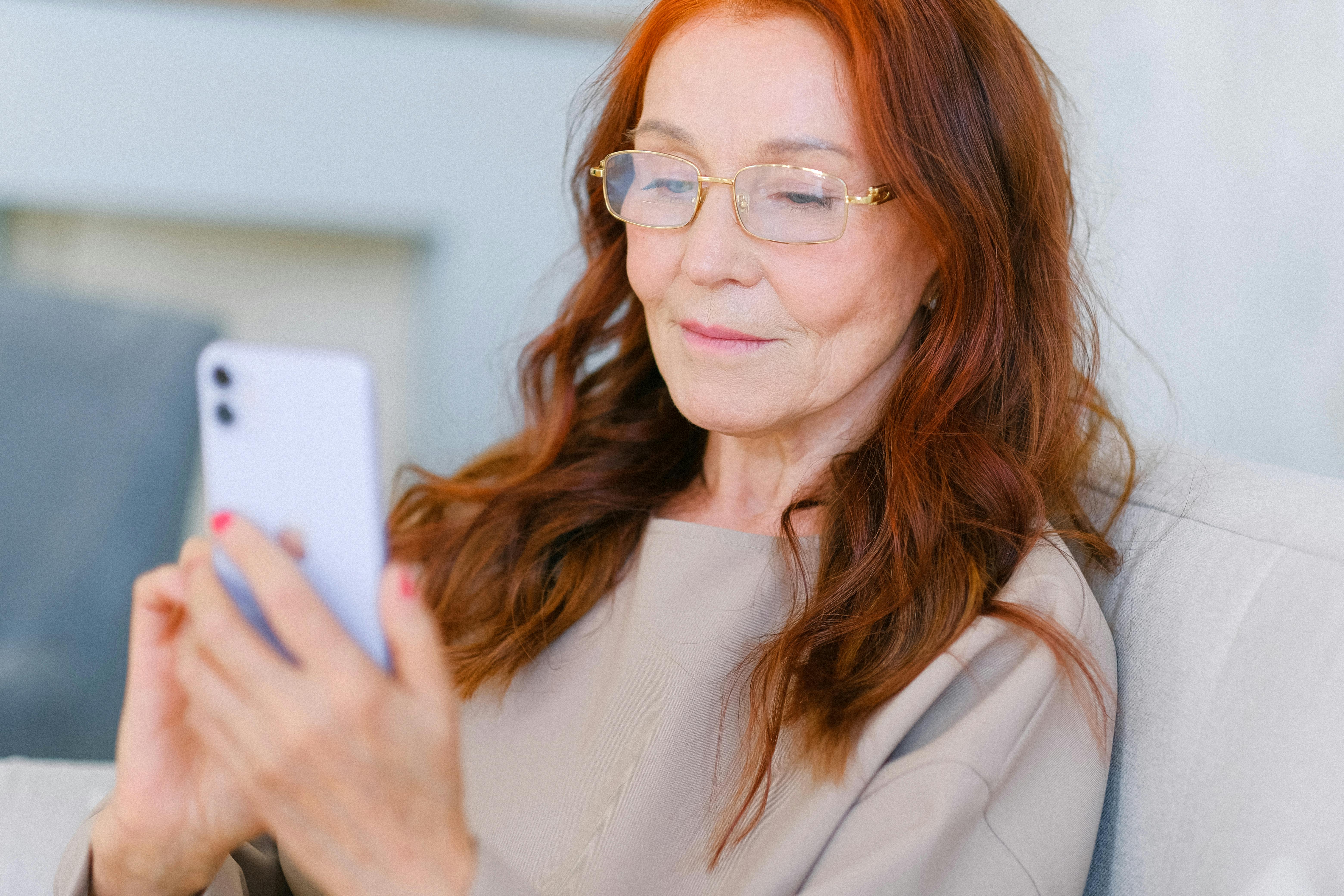Elder woman with red hair looking at smartphone
