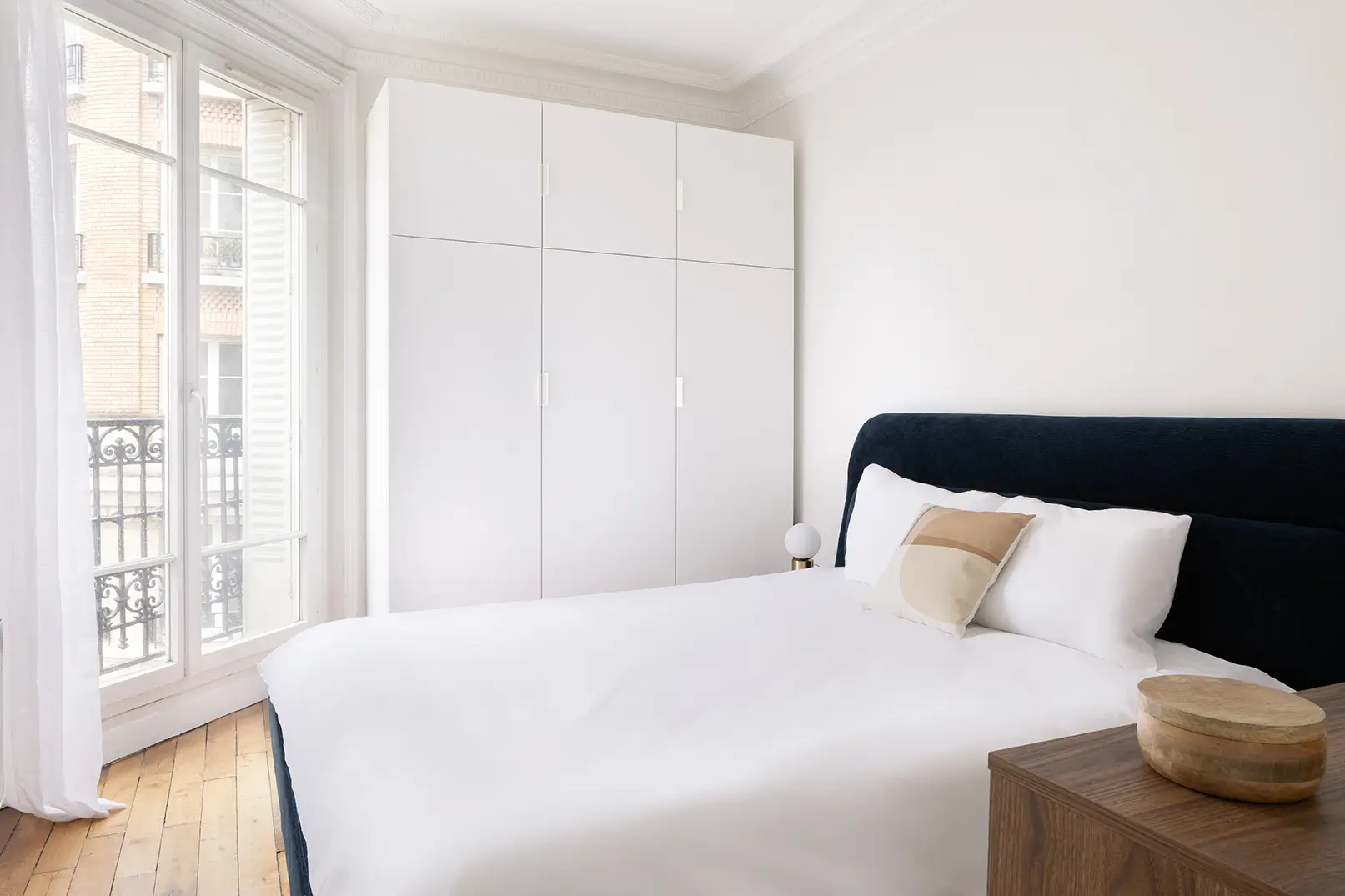 Un lit avec des draps blancs dans une chambre avec fenetre.