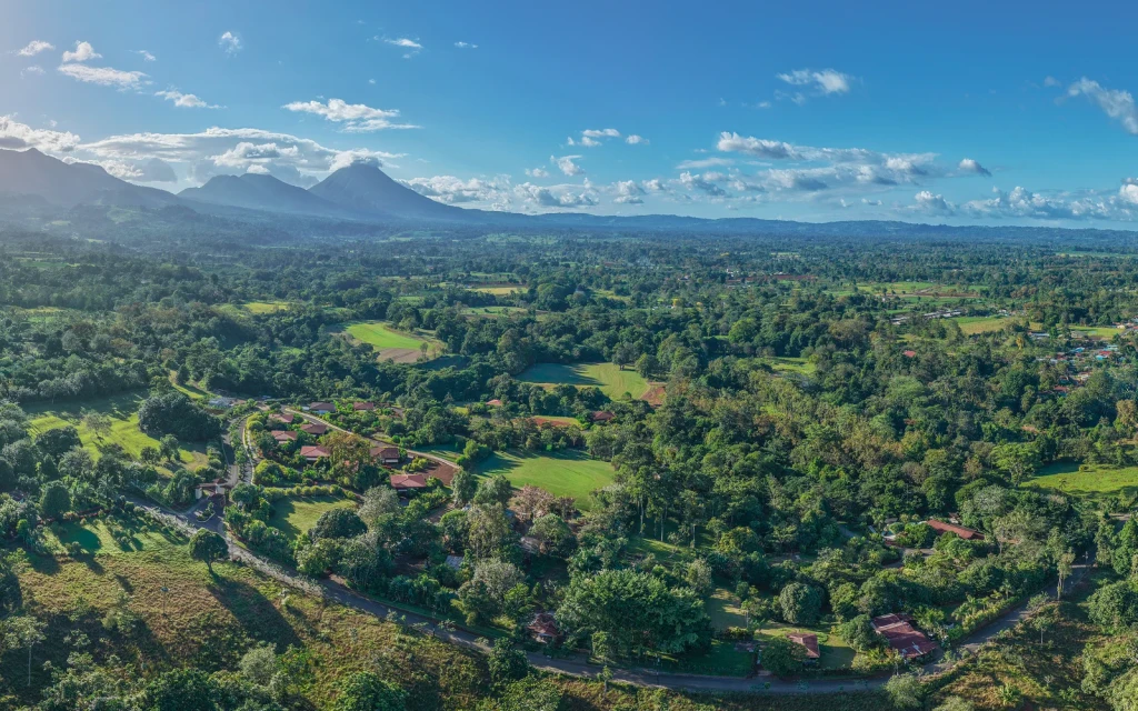 A drone photo of Arenal Hills from above, with the Arenal volcano in the distance