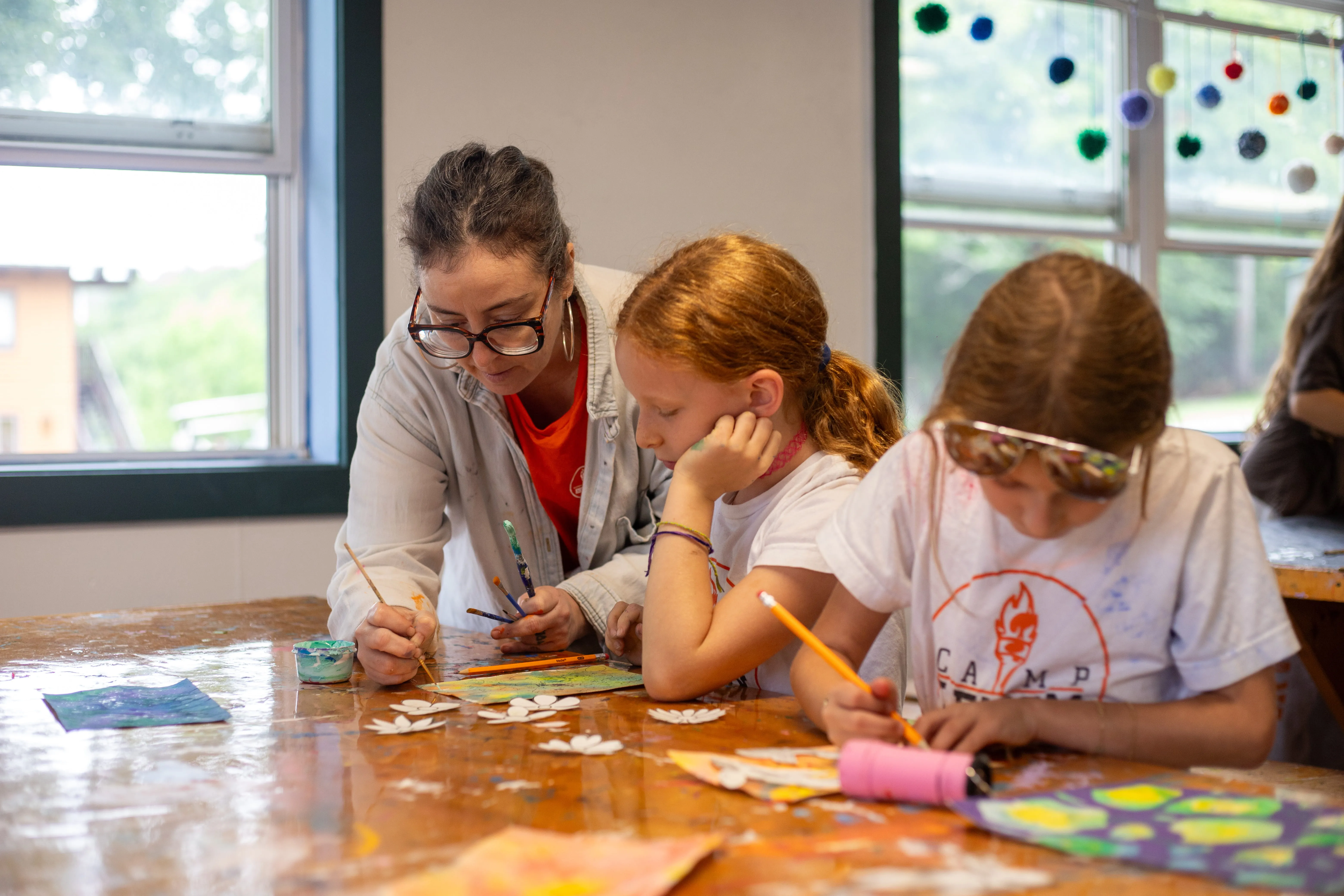 Art instructor helping campers with a drawing project indoors
