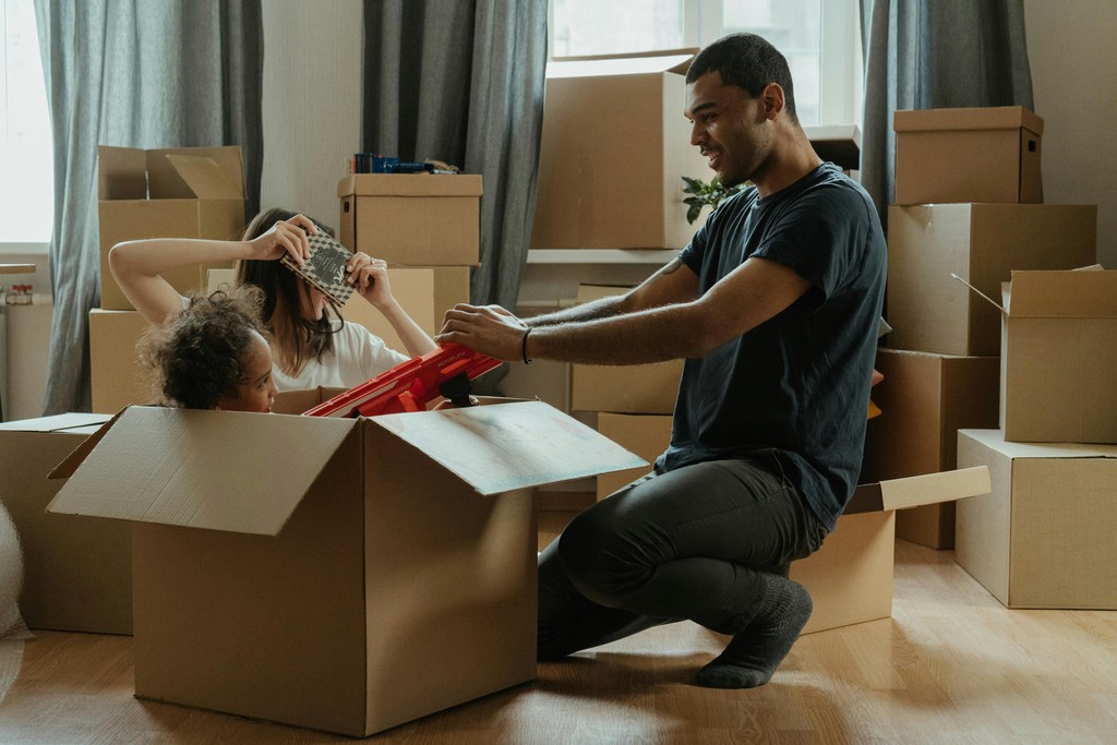 Newcomer family in Canada feeling stressed while reviewing a rental agreement next to moving boxes.