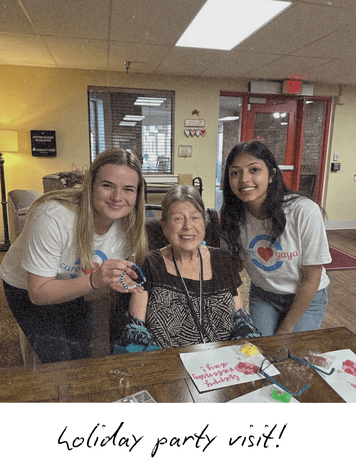Polaroid of two CareYaya students and an older adult woman making crafts at assisted living facility