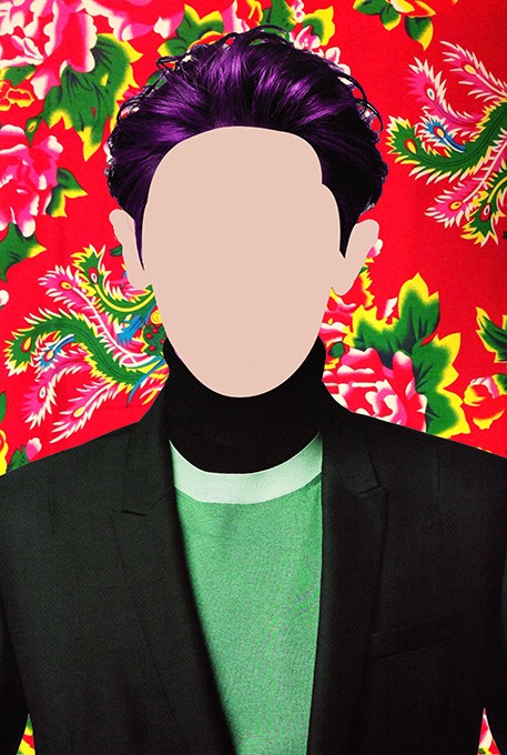 The image shows a person with vibrant purple hair against a red background adorned with pink and green floral patterns. The individual wears a black turtleneck and a green shirt underneath a black blazer. The face is obscured by a light beige or off-white shape. The person’s hair is styled in a way that partially covers the forehead, and the image focuses on the upper body. No other objects or text are visible in the image.