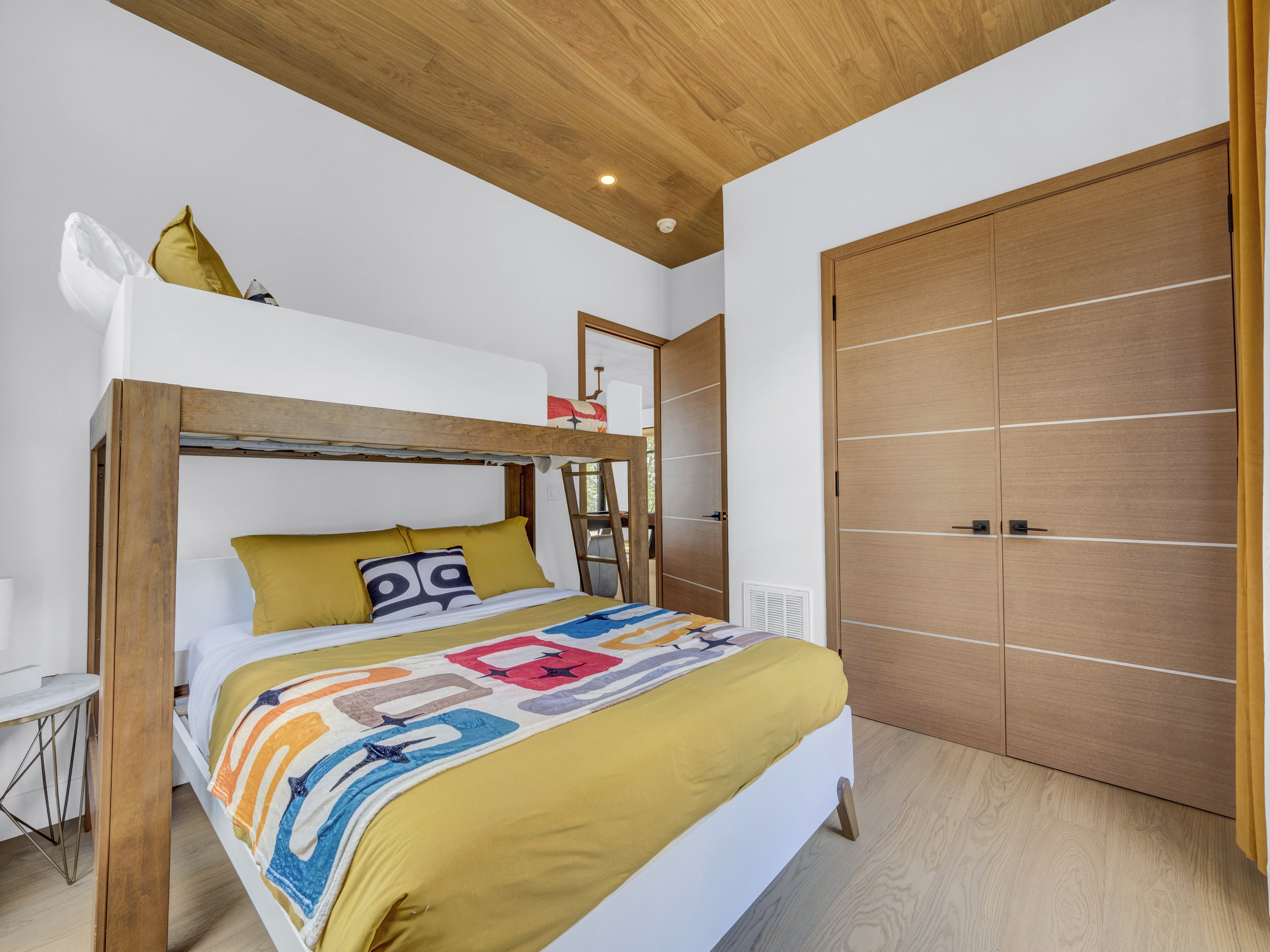The bunk room featuring a custom wooden bunk bed and large built-in light wood closets