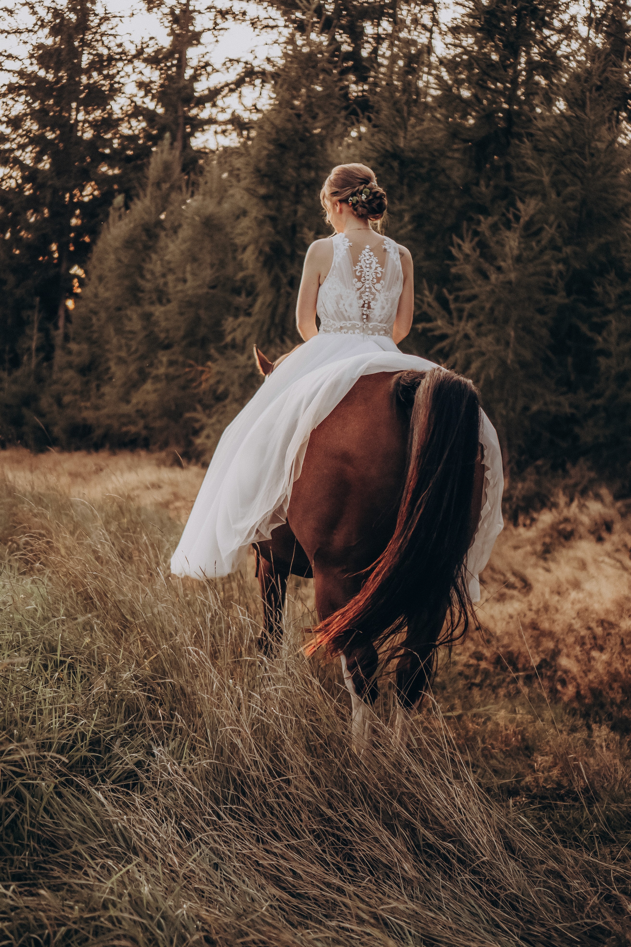 Braut reitet auf einem Pferd durch den Wald bei Bogen – Märchenhafte Hochzeitsfotografie.