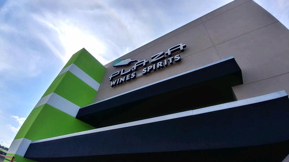 Signage on a modern building with a green and gray design under a clear blue sky.