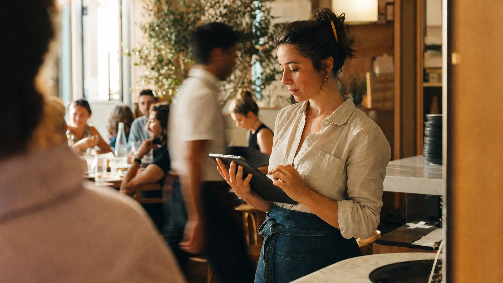 Responsabile di sala aggiorna il menu digitale sul tablet al passe durante il servizio di pranzo
