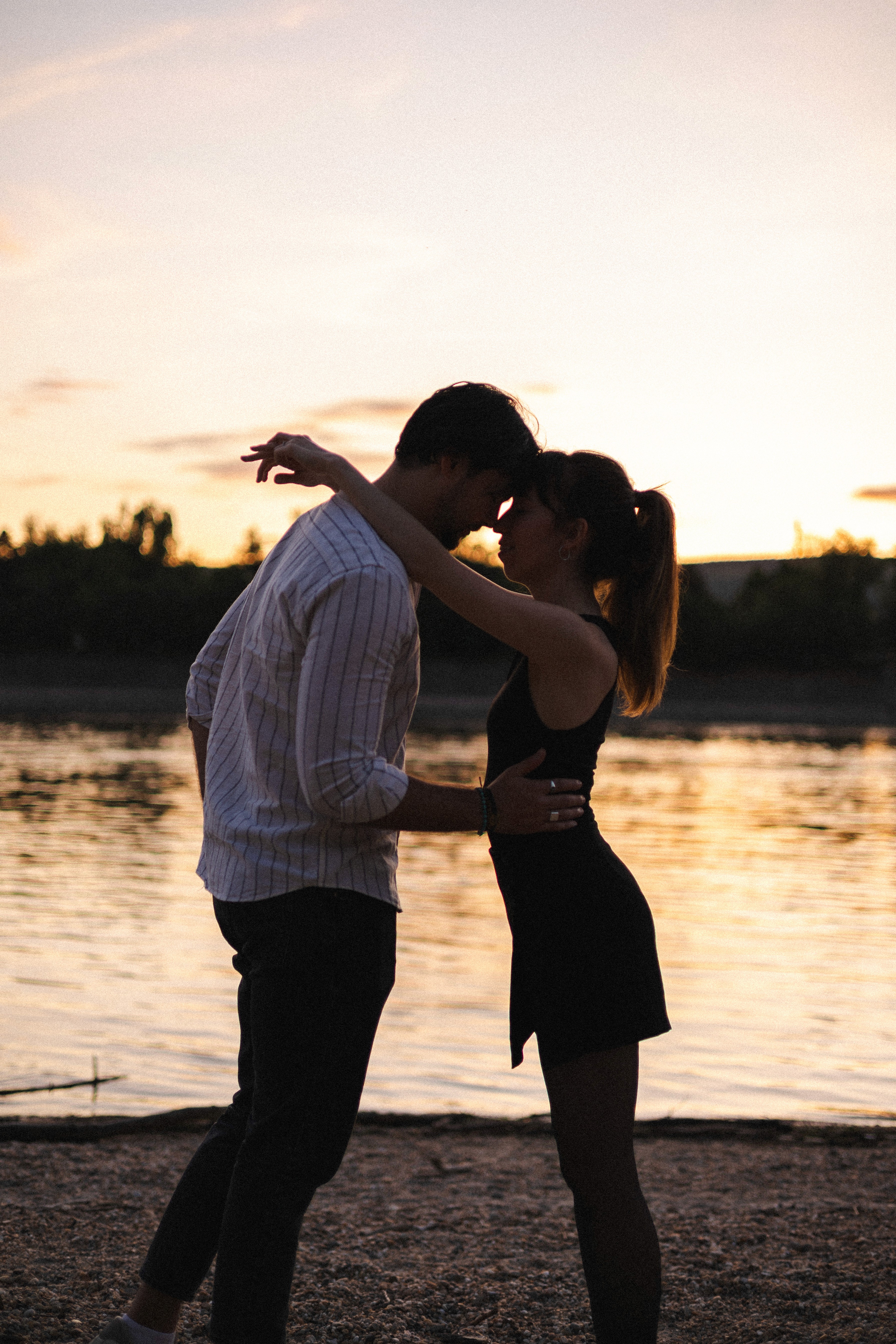Woman practicing yoga warrior pose on a wooden platform surrounded by forested mountains in early morning light.