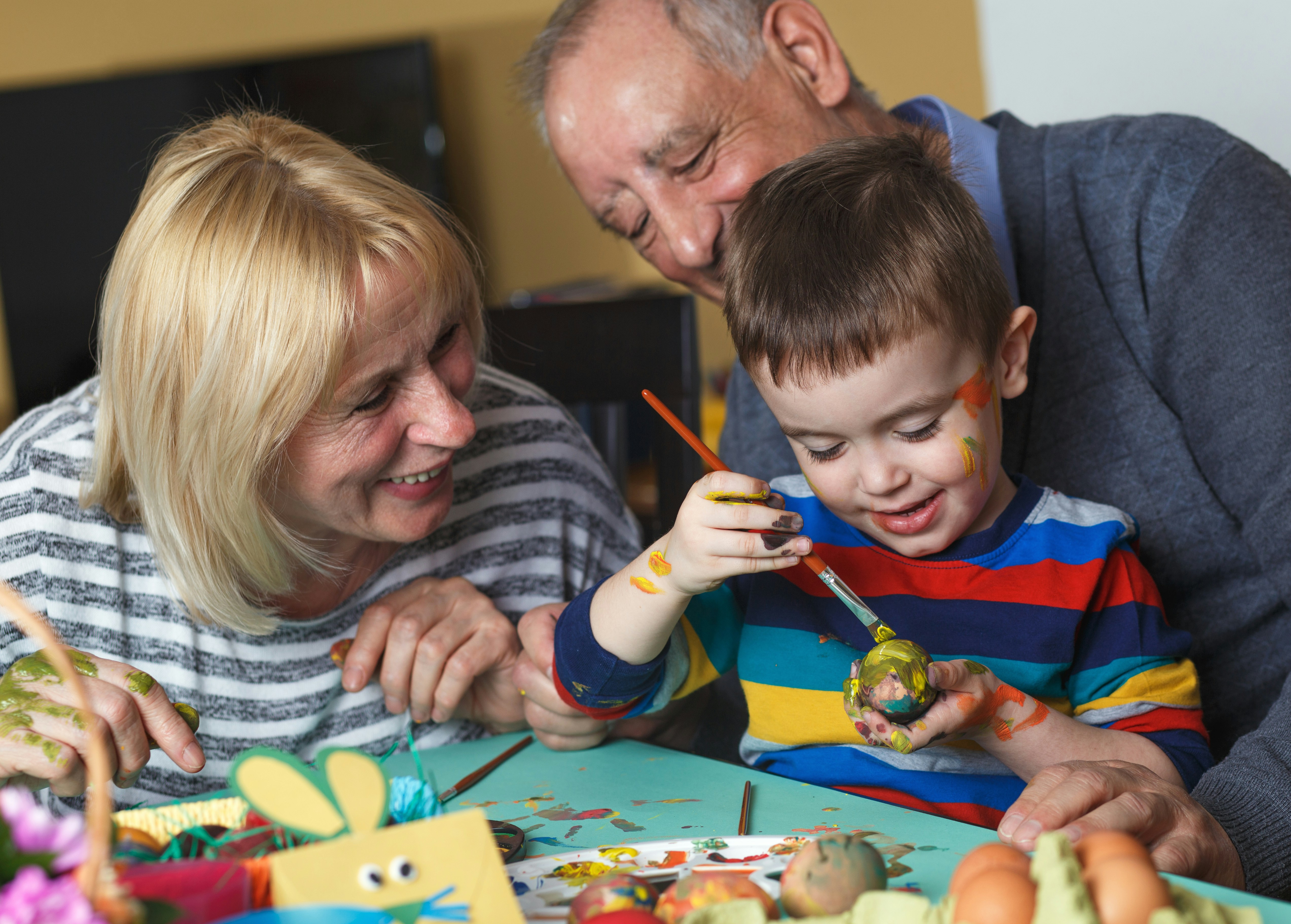 grandson paints egg as grandparents watch