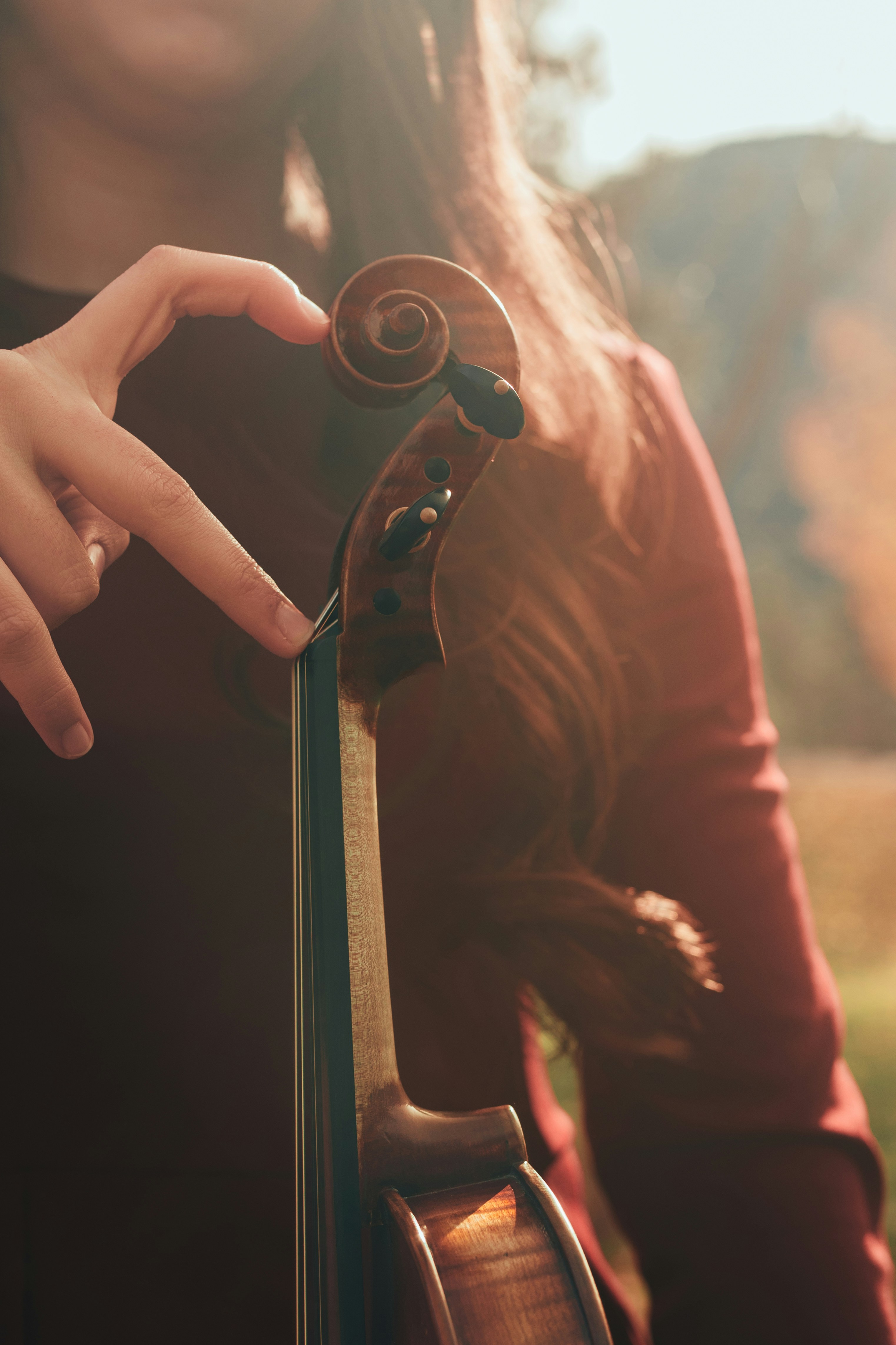 Woman lovingly holds a violin outdoors.