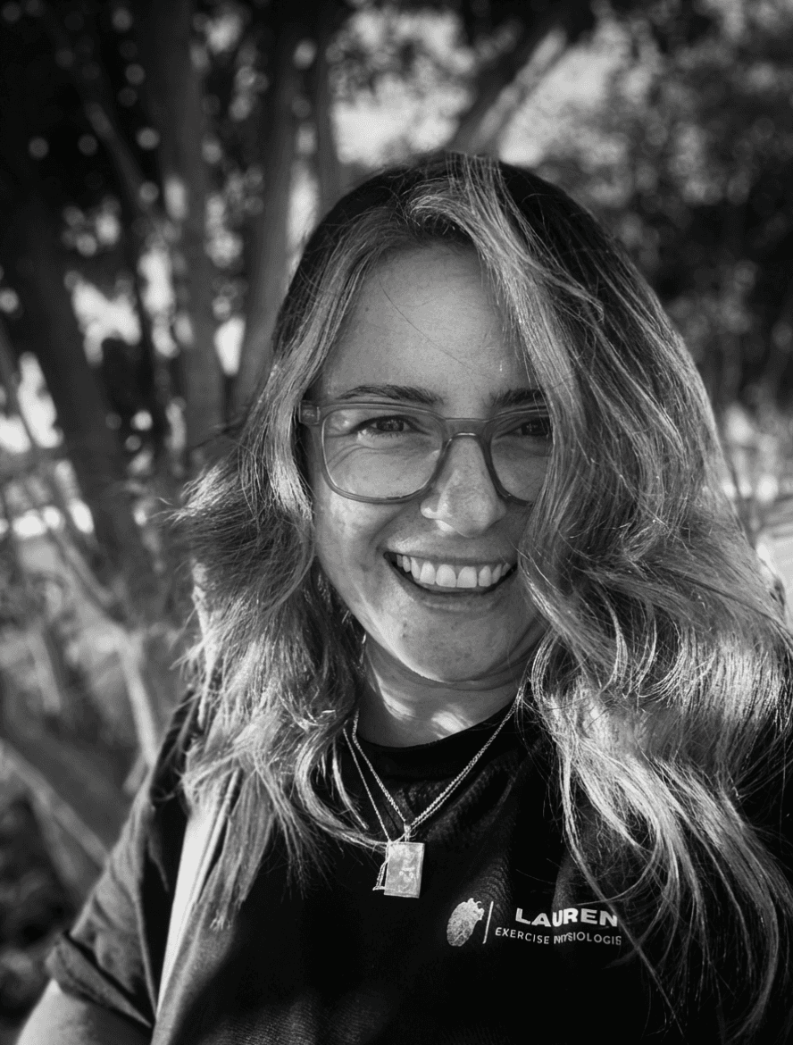 A serene outdoor seating area with two chairs, surrounded by lush greenery and a glassed-in structure.
