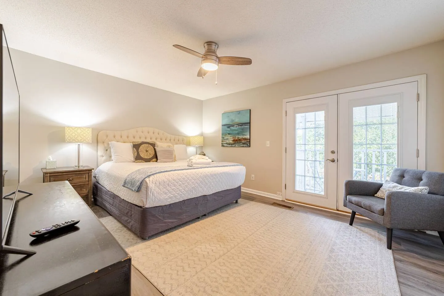 King suite with an upholstered headboard, armchair and French doors