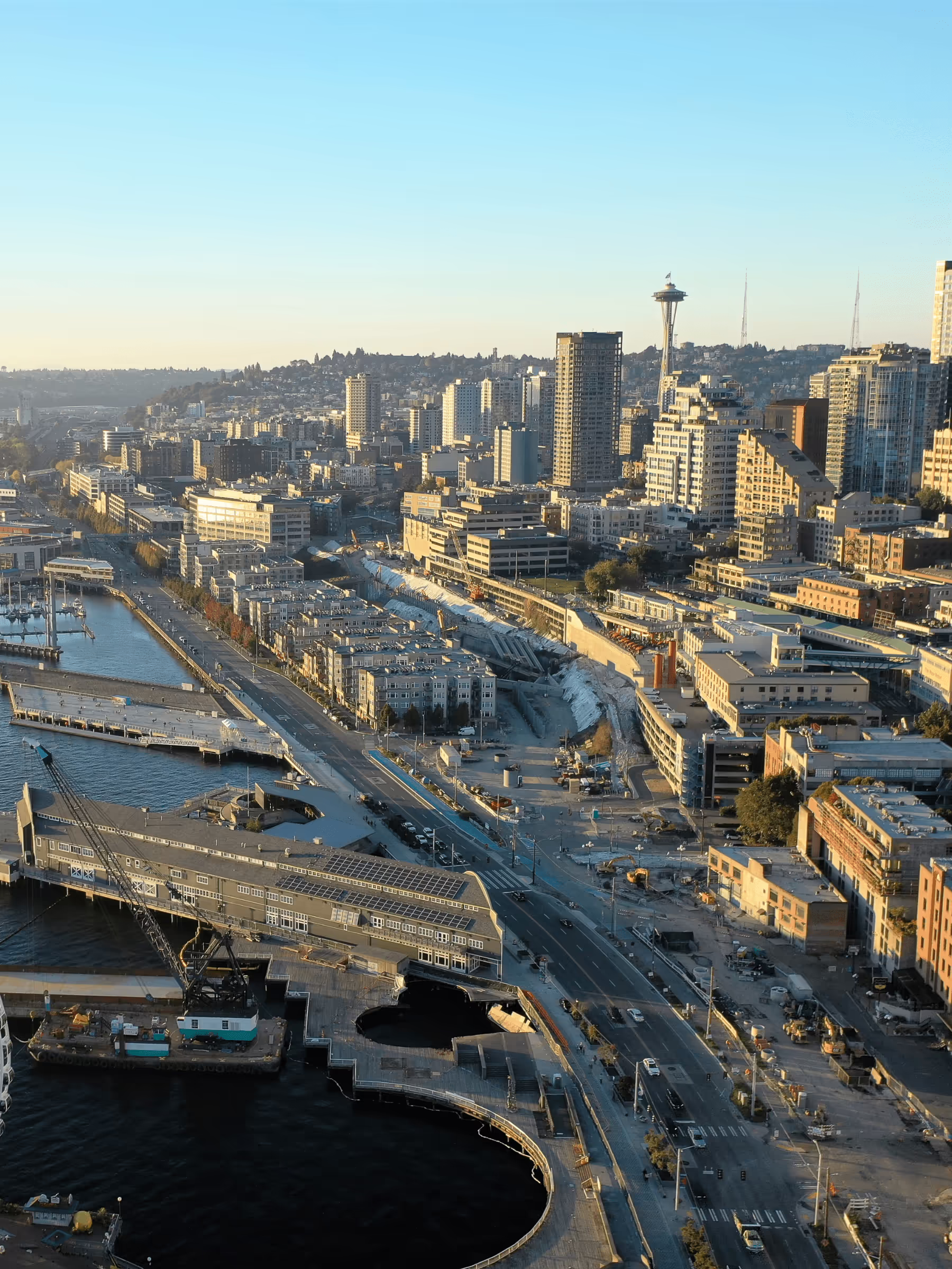 Urban cityscape with iconic tower and waterfront area under clear blue skies.