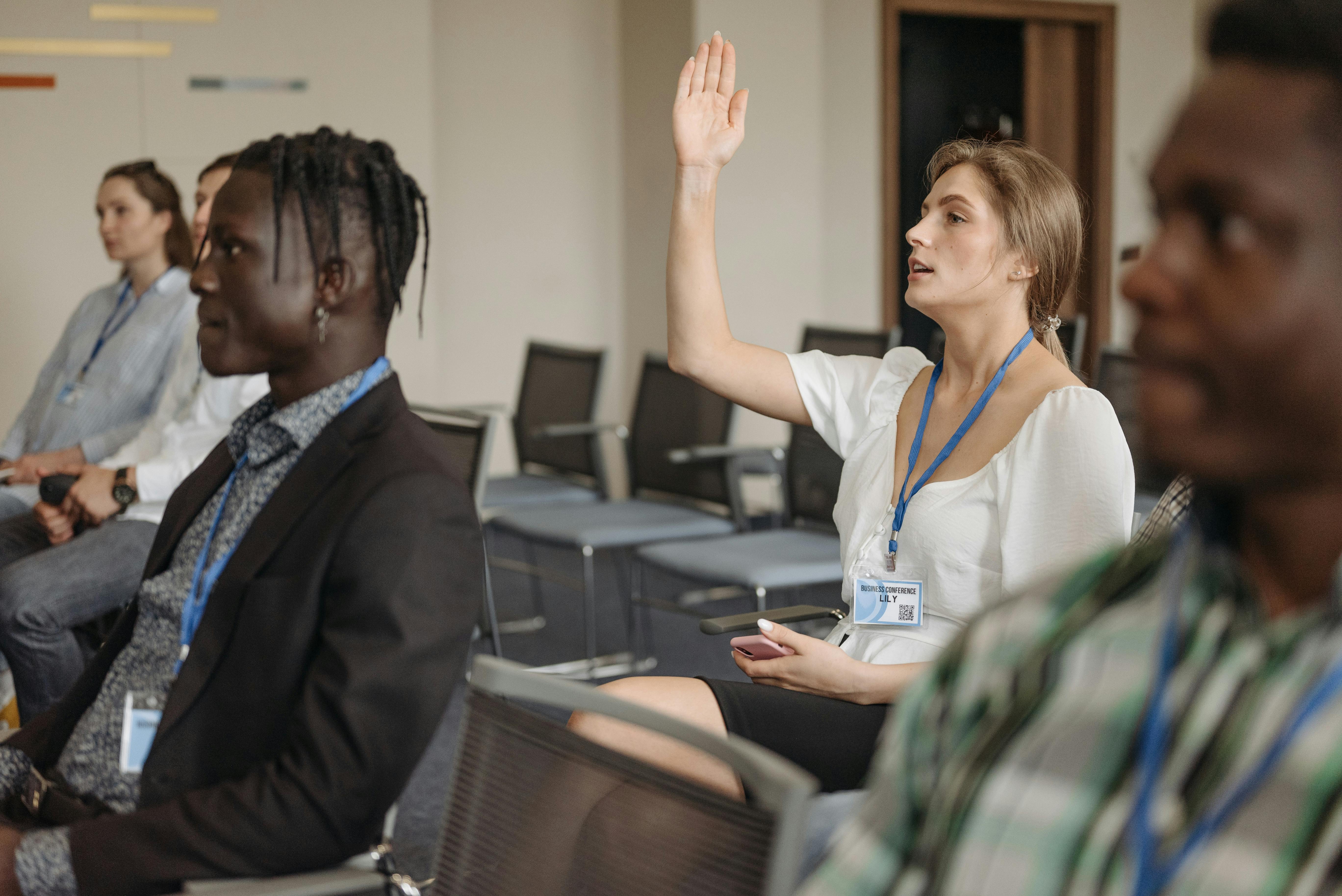 A woman raising her hand to ask a question to a mentor.