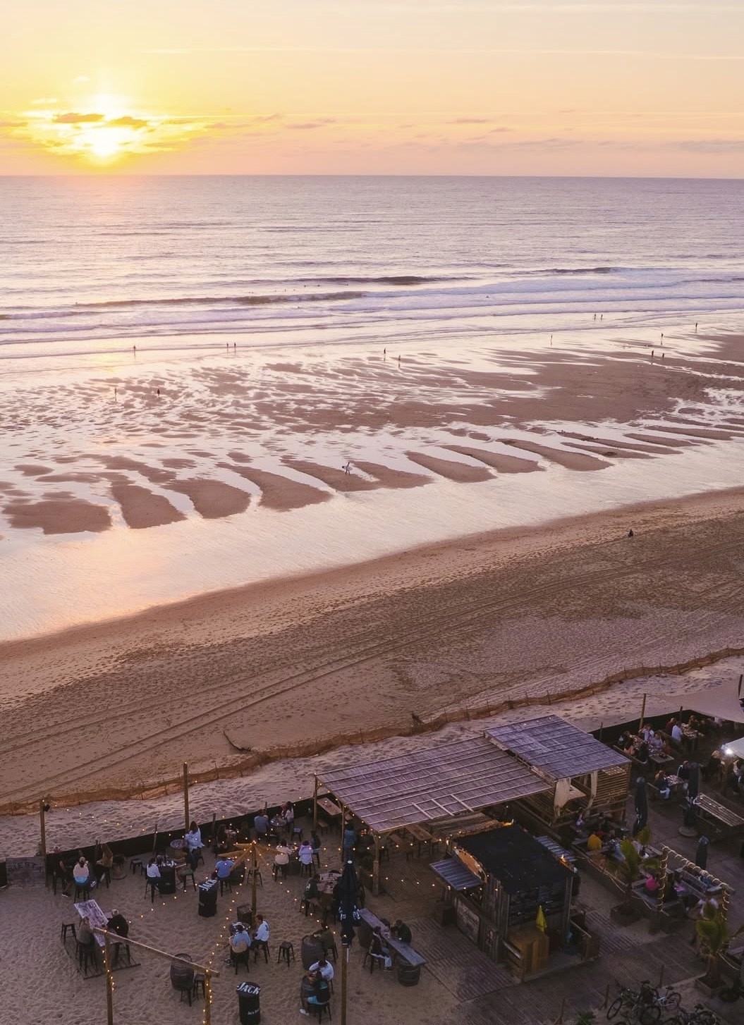 A serene outdoor wedding setup with white chairs arranged on green grass under a canopy of trees.