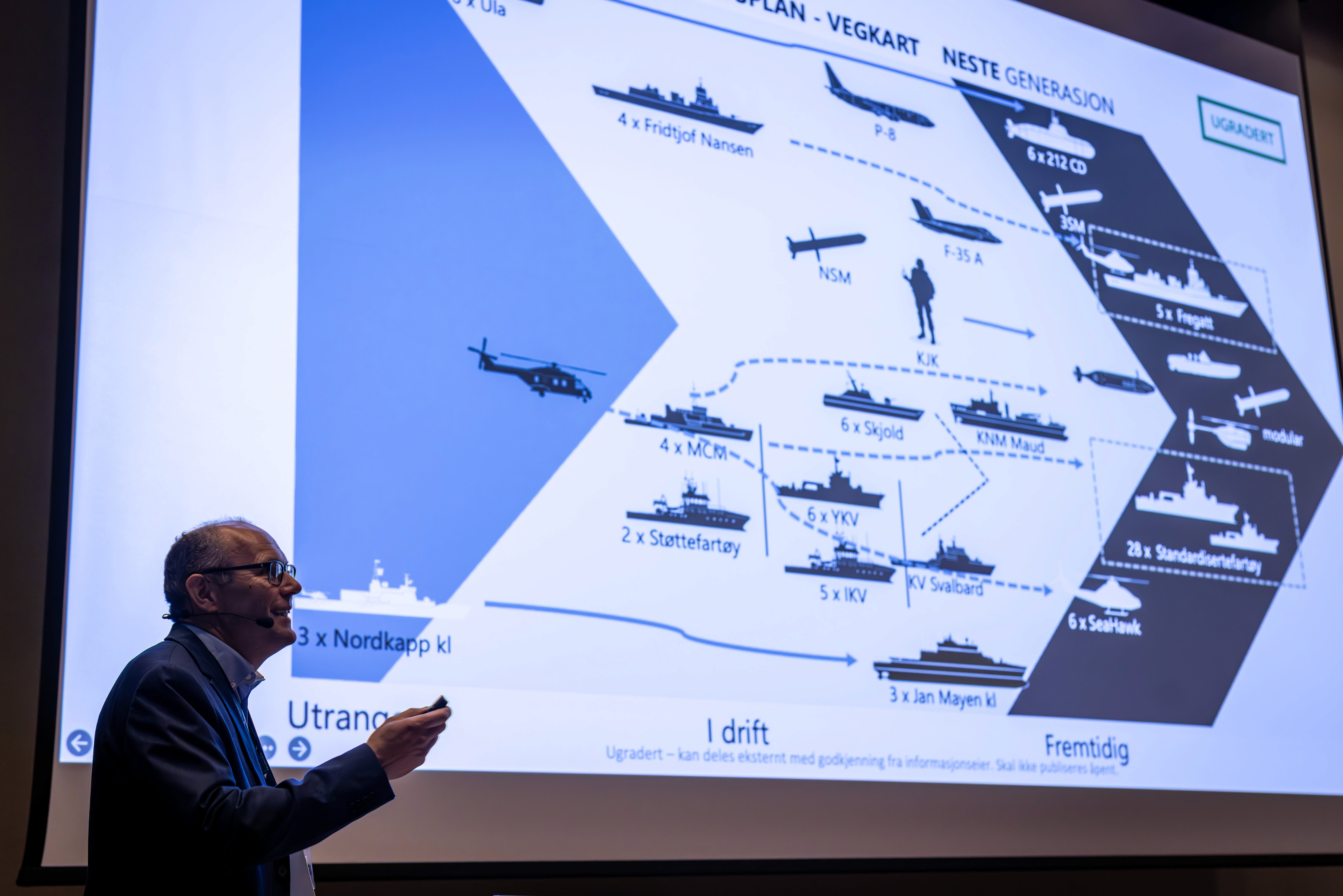 A person gestures toward a projection displaying diagrams or charts, possibly related to technology or data analysis.