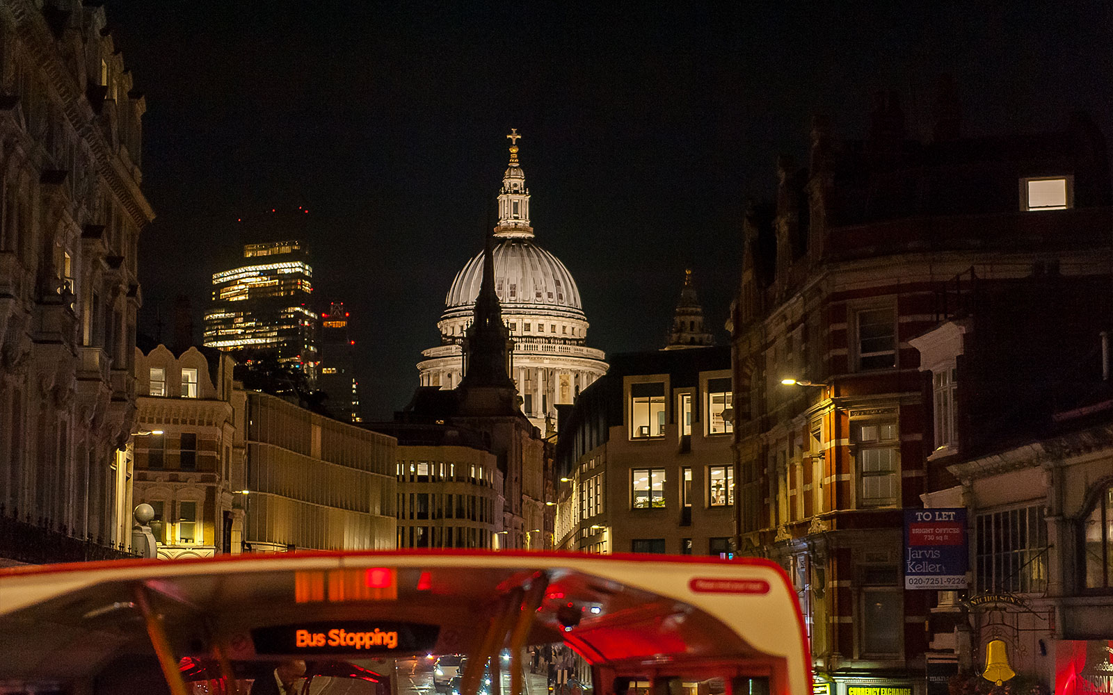 Bus à arrêts multiples à Londres la nuit avec la cathédrale Saint-Paul en arrière-plan.