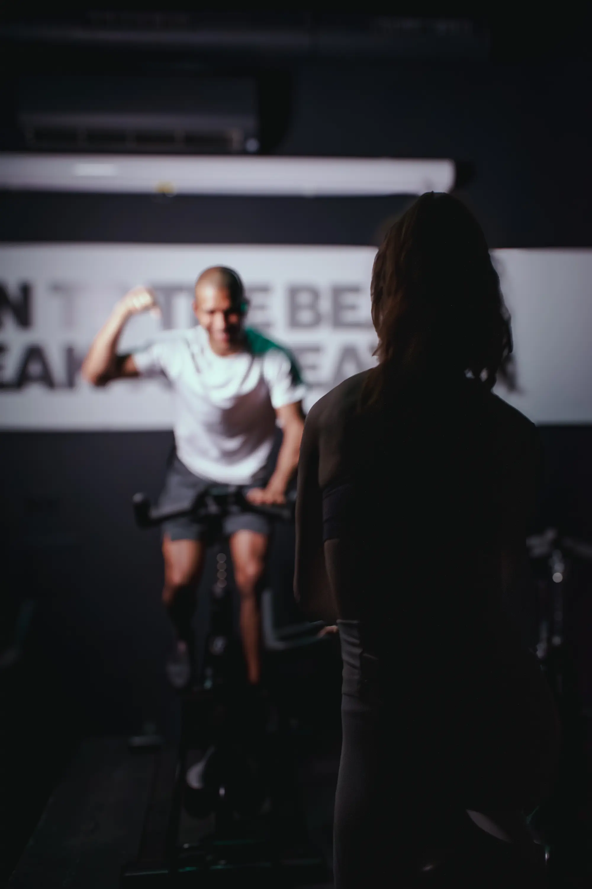 Coach et participant en pleine séance d’indoor cycling immersive chez Spinbreak à Bordeaux, ambiance sombre et motivante
