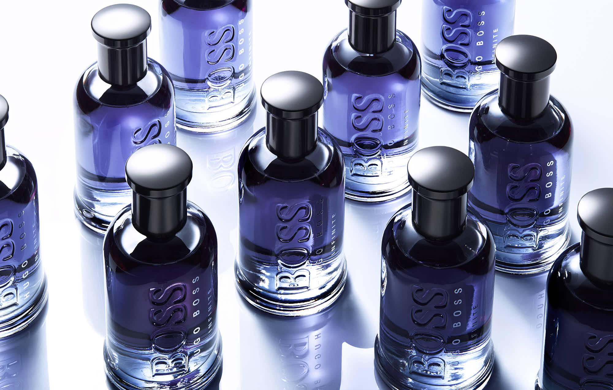 A collection of small glass bottles with silver caps, reflecting light, arranged on a reflective surface.