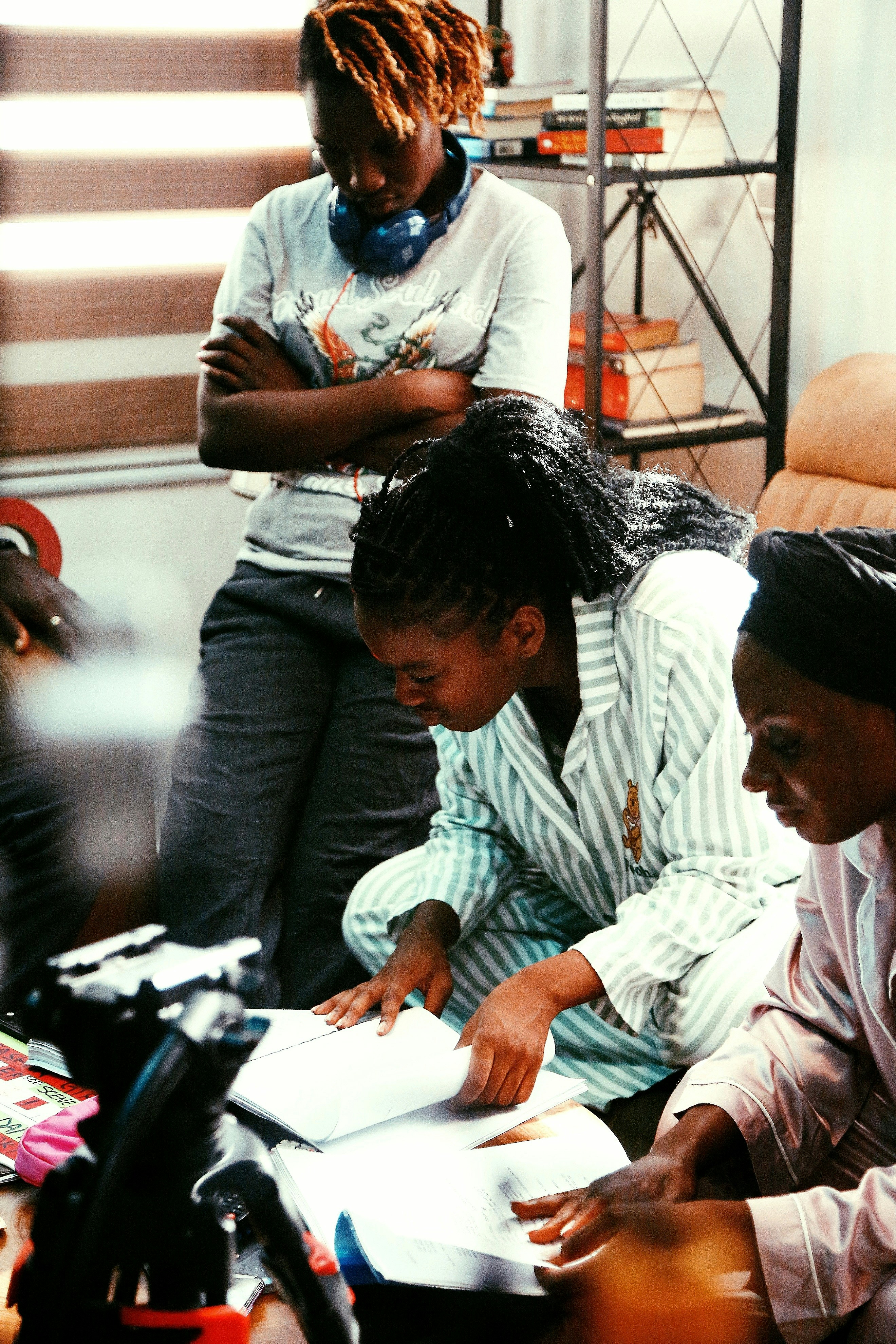 Three women review papers together indoors.