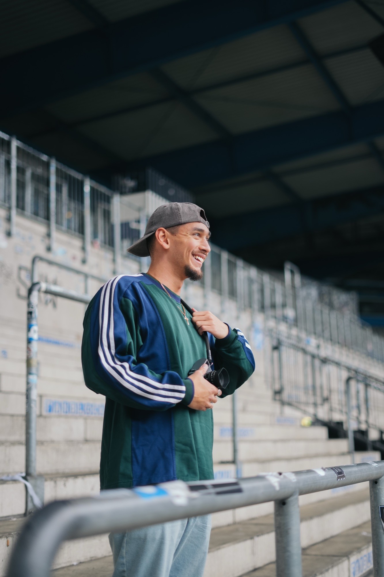 Mann mit Kamera auf der Tribuene eines Stadions