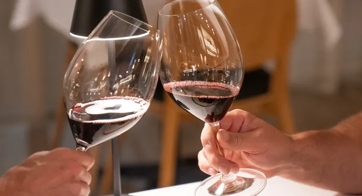 Two guests toasting with red wine glasses at Annata Restaurant