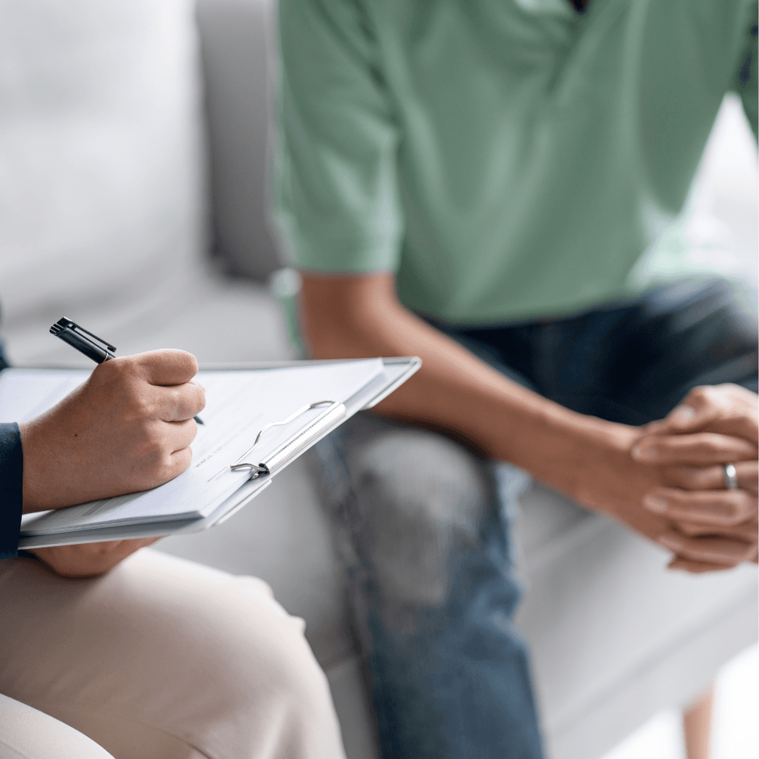 Doctor listening patiently to a male patient and taking notes