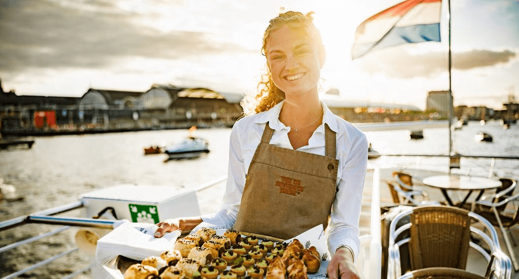 Hospitalitymedewerker serveert luxe cateringhapjes tijdens event op boot in Amsterdam