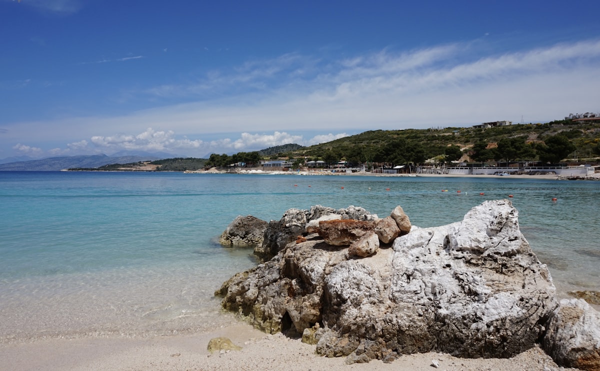Turquoise water lapping a rocky Albanian coastline with cliffs in the background