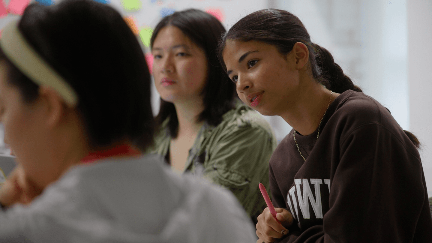 High school student reviewing the Brown Leadership Institute program guide with college application materials