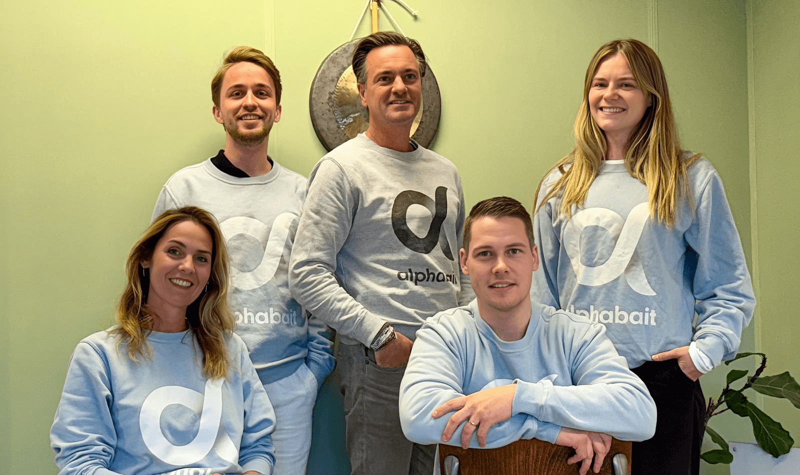 An image showcasing the current team of Alphabait. 2 people are sitting on chairs in front and 3 people are standing behind them.