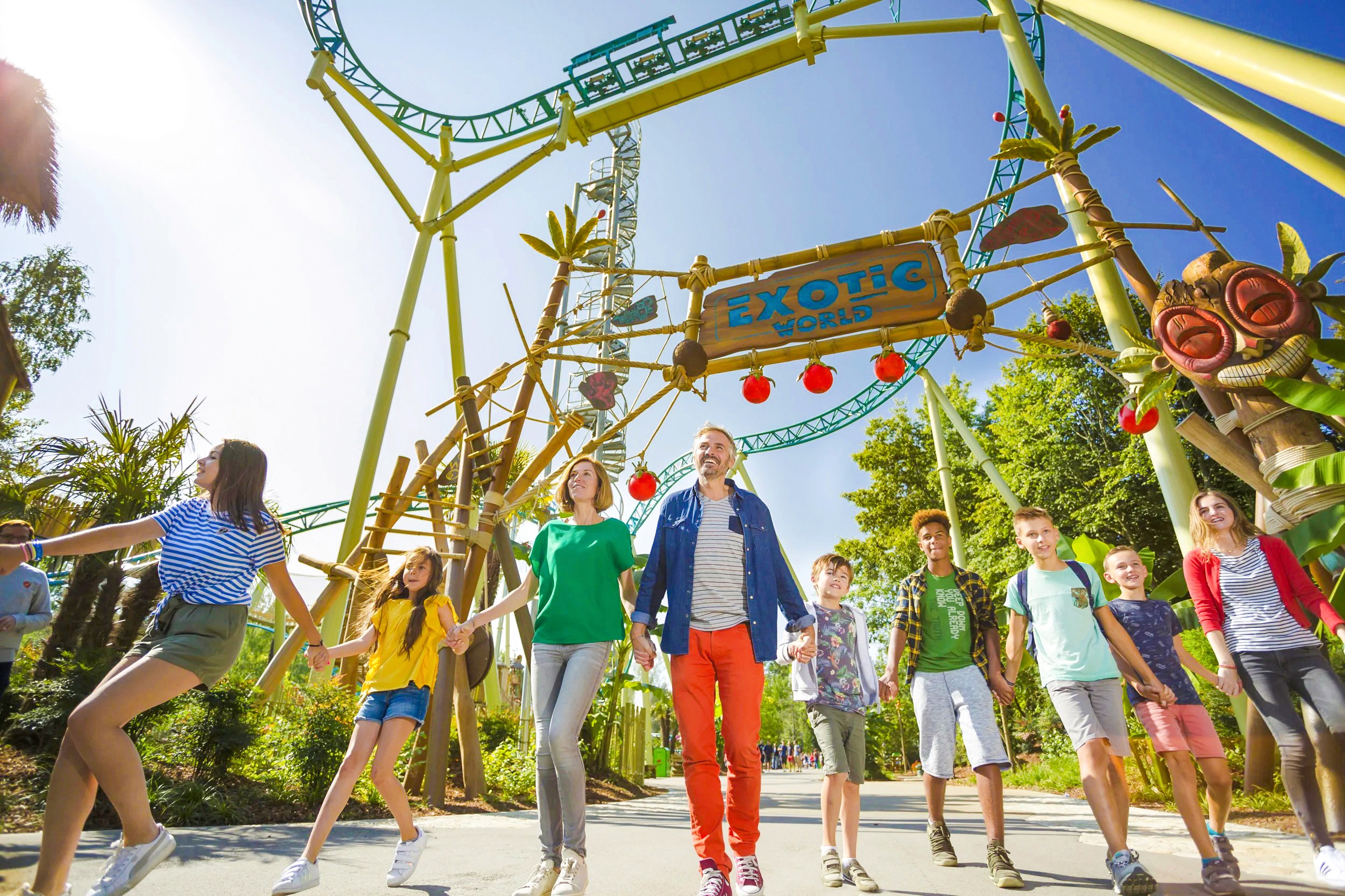 Látogatók fedezik fel az Exotic World vidámpark bejáratát, miközben a hullámvasút magaslik felettük.