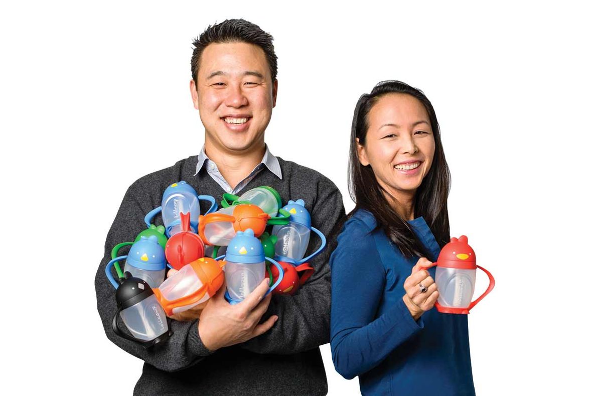 Two smiling people hold colorful bottles and containers, standing against a white background.