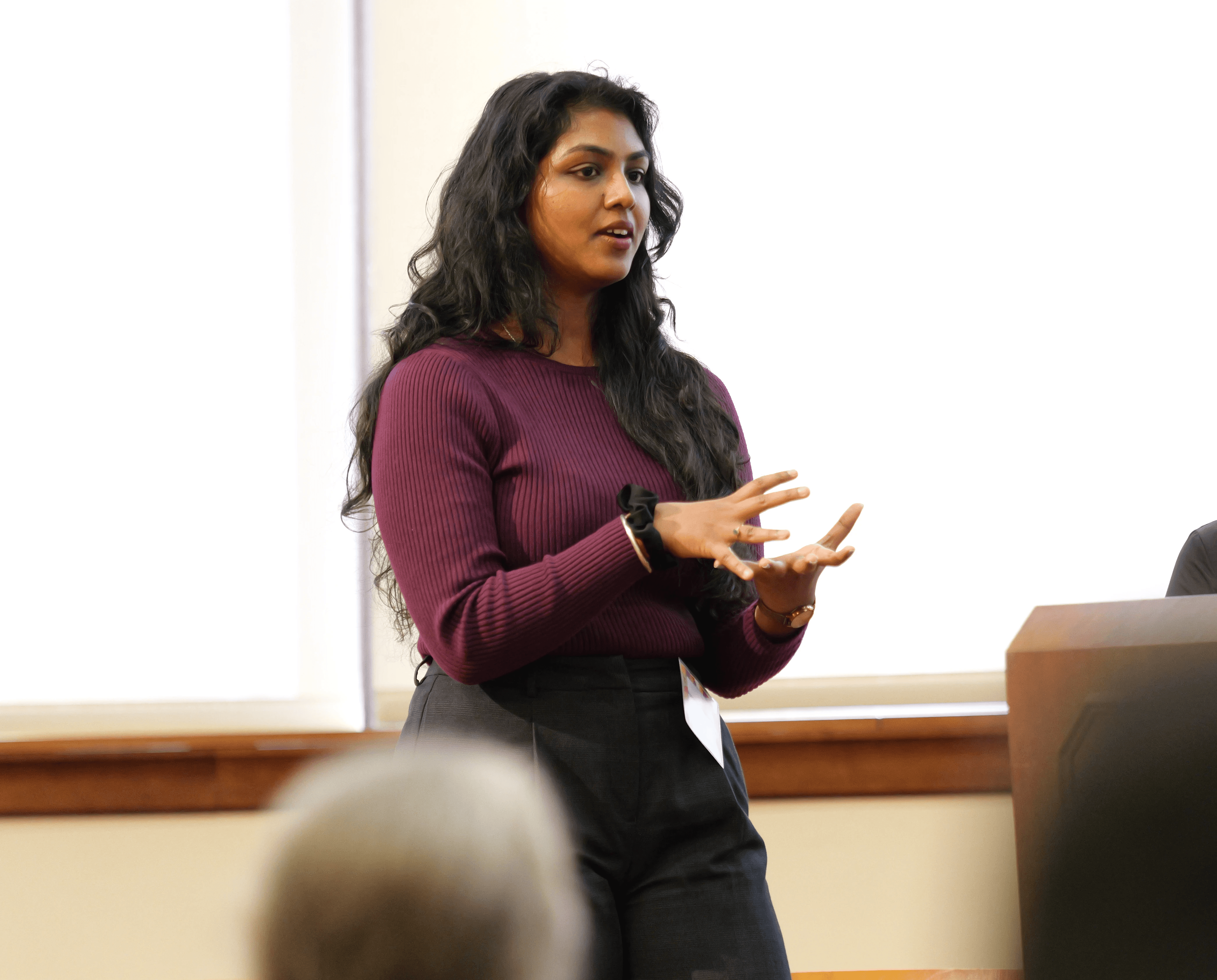Young woman speaking passionately at a podium with her hands gesturing.