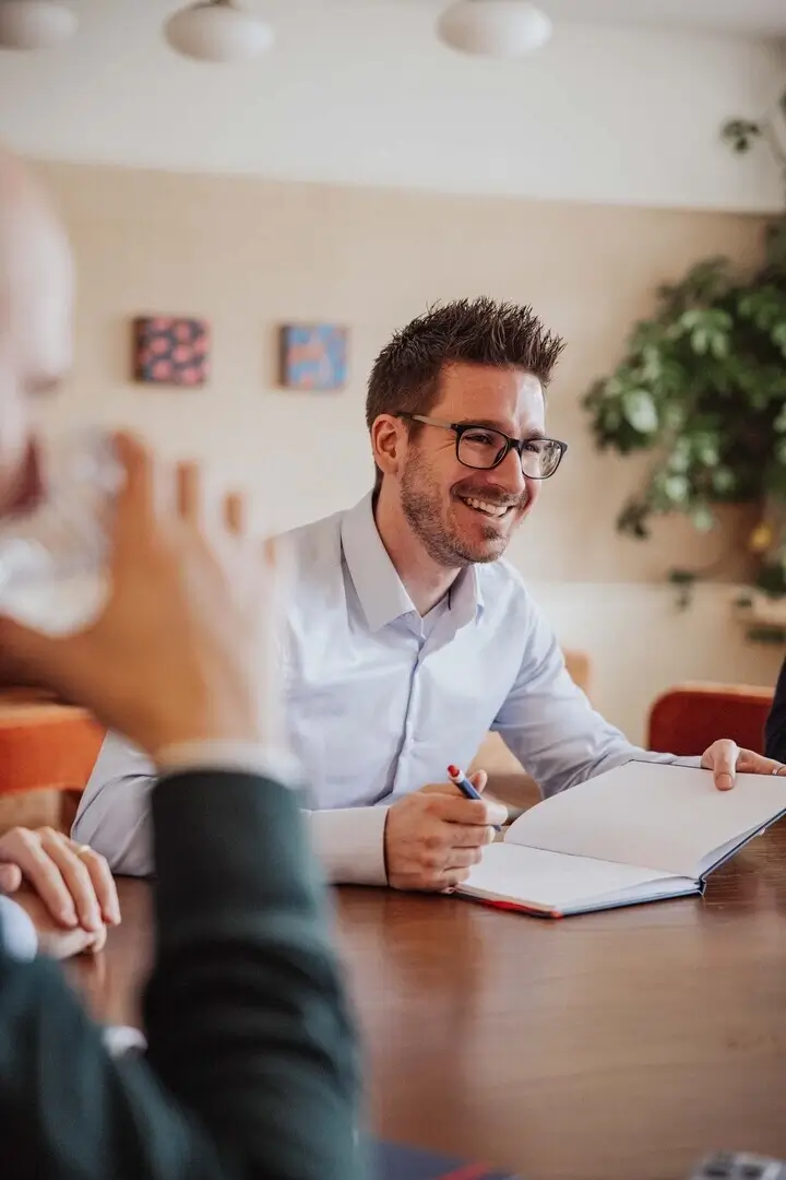 Professionelle Gastronomie- & Interieur-Fotografie: Gemütliche Lounge-Ecke mit rotem Sessel und beleuchteter Wein-Präsentation, inszeniert mit warmem Ambient-Licht und Fokus auf Design-Details.