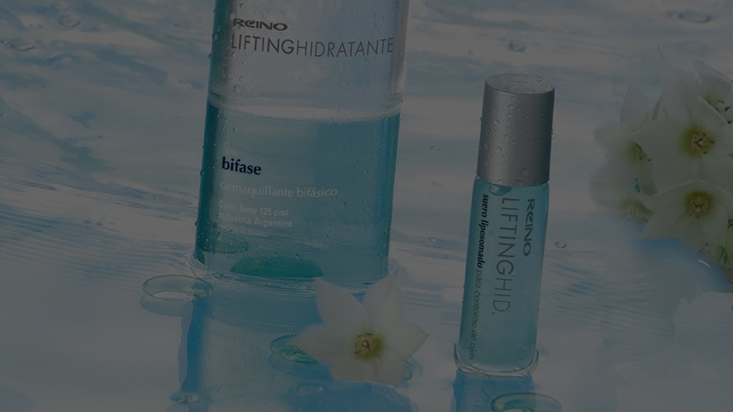 Transparent bottles of Reino skincare products, partially submerged in water with delicate white flowers floating nearby, creating a fresh and calming atmosphere.