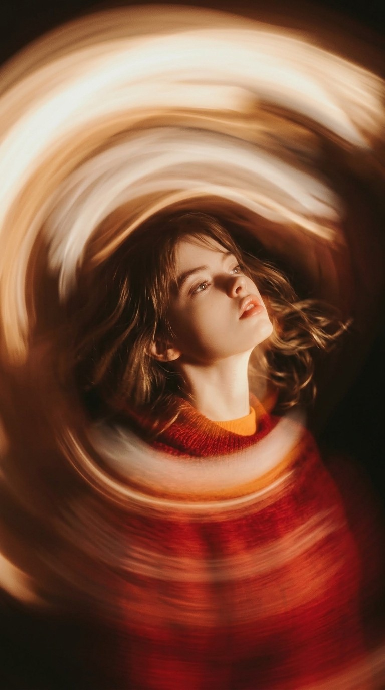 Dynamic portrait of a woman looking upward with motion-blurred light effects