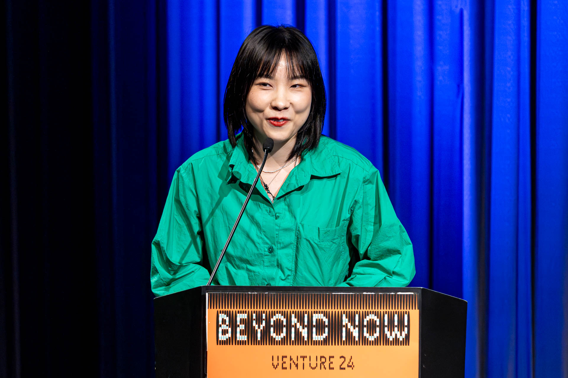 a student at a podium presenting a project in a Theatre