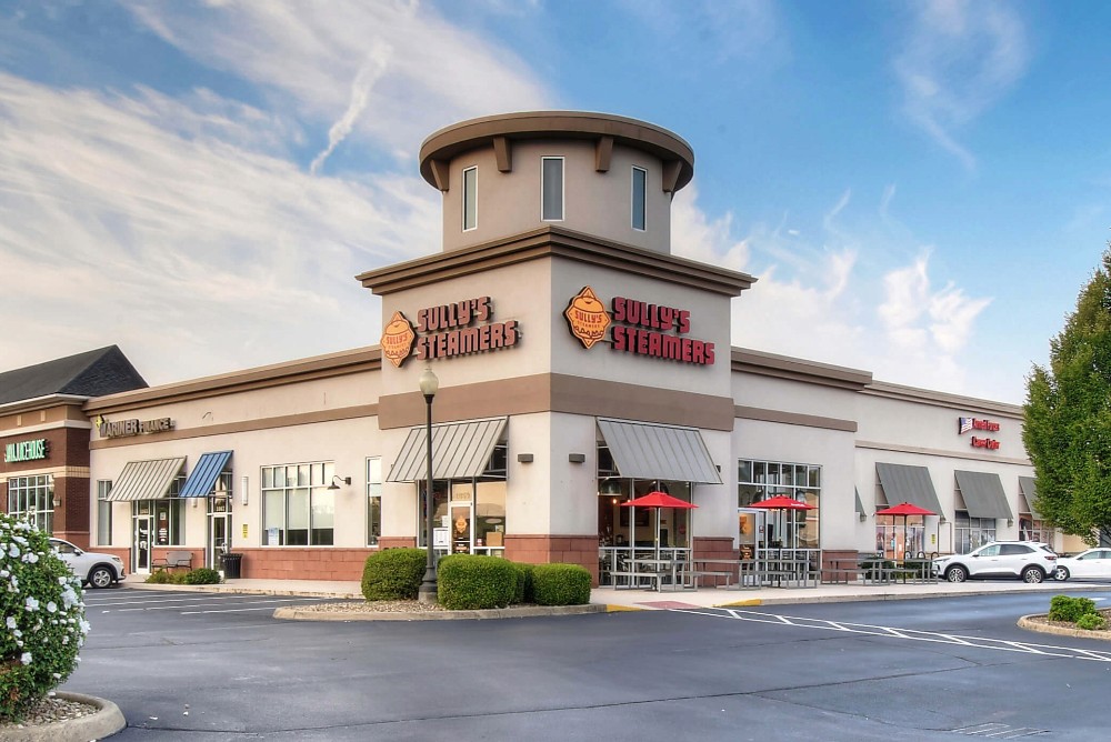 Exterior view of a restaurant with a round tower, surrounded by a parking lot and blue sky.