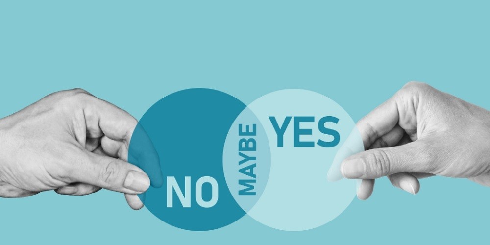 A conceptual Venn diagram held by two hands against a teal background. One circle is dark blue with the word 'NO', the other is light blue with 'YES', and the overlapping section reads 'MAYBE'